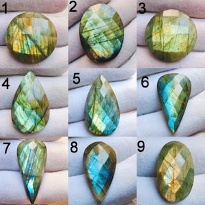 May include: Nine faceted labradorite gemstones in various shapes, including round, oval, and teardrop. The stones display a mix of green, blue, and gold iridescence. Each gem is cut to showcase its natural colors and patterns, perfect for jewelry making.
