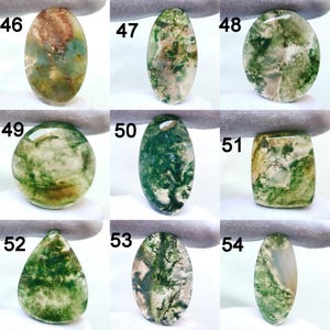 May include: Nine polished moss agate gemstones in various shapes, including oval, round, and teardrop. The stones display green, brown, and white patterns, resembling landscapes. Each stone is numbered for identification.