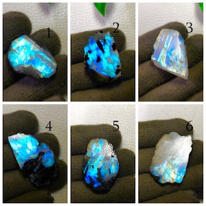 Puede incluir: Una colección de seis piedras preciosas de labradorita en bruto, cada una mostrando un vibrante juego de colores. Las piedras varían en forma y tamaño, con destellos de azul, verde y dorado. Las piedras preciosas se muestran sobre un fondo oscuro.