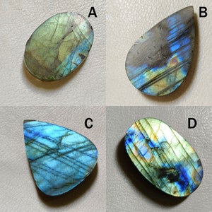 Peut inclure: Quatre cabochons de labradorite en forme et couleur diff&eacute;rentes. Les cabochons sont &eacute;tiquet&eacute;s A, B, C et D. Les cabochons sont tous iris&eacute;s et pr&eacute;sentent une vari&eacute;t&eacute; de couleurs, notamment le vert, le bleu et l'or.