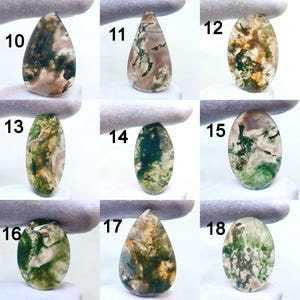 May include: A collection of nine moss agate gemstones, each with unique patterns of green, brown, and white. The stones vary in shape, including oval and teardrop designs. Each stone is numbered from 10 to 18.