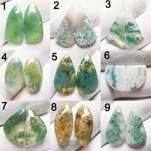 May include: A collection of nine pairs of polished gemstone cabochons, each with unique patterns and colors. The stones vary in shape, including teardrop, oval, and triangular forms. Colors range from shades of green, blue-green, and brown, with intricate internal veining.