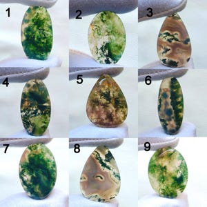 Puede incluir: Nueve piedras preciosas de ágata musgosa pulidas en varias formas. Las piedras muestran una gama de colores, incluyendo verde, marrón y blanco, con patrones únicos que se asemejan a paisajes. Cada piedra se sostiene sobre un fondo blanco.
