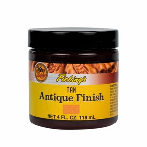Puede incluir: Un tarro de 118 ml de tinte para cuero Fiebing's Tan Antique Finish. El tarro es amarillo con letras negras y una tapa marr&oacute;n.