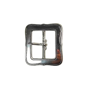 Puede incluir: Hebilla de cinturón de metal plateada con forma cuadrada y un borde decorativo festoneado.