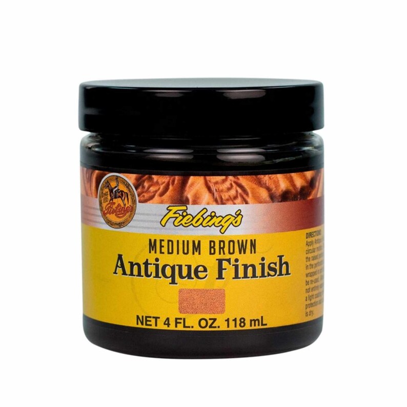 Puede incluir: Un tarro de 118 ml de tinte para cuero Fiebing's Medium Brown Antique Finish. El tarro es amarillo con letras negras y una tapa marr&oacute;n.