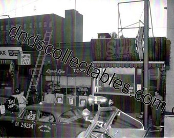 May include: A black and white photo of a diner with a taxi parked in front. The diner has a sign that says "Laurel Line" and "Butter Toast". The taxi has a sign that says "Taxi 2-9234".