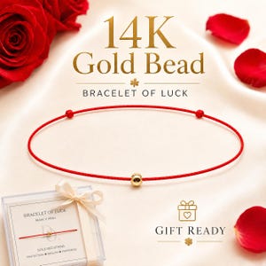 Puede incluir: Una pulsera de hilo rojo con una cuenta de oro de 14K y dos nudos dorados más pequeños. Se muestra el texto 14K Gold Bead Bracelet of Luck y Gift Ready. La pulsera se presenta con una caja de regalo transparente y pétalos de rosa rojos.