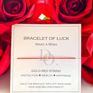 May include: Red string bracelet with a gold bead and the words "BRACELET OF LUCK" and "MAKE A WISH" on a white card. The card also says "GOLD RED STRING", "PROTECTION WEALTH HAPPINESS", and "ONCE THE BRACELET RIPS OFF YOUR HAND, YOUR WISH BECOMES REALITY".