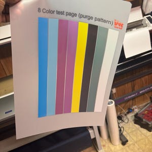 May include: A white sheet of paper with 8 colour test strips. The strips are blue, light blue, purple, yellow, black, grey, and white. The text "8 Colour test page (purge pattern)" is printed at the top of the page. The text "WKS Wrap" is printed in the top right corner of the page.