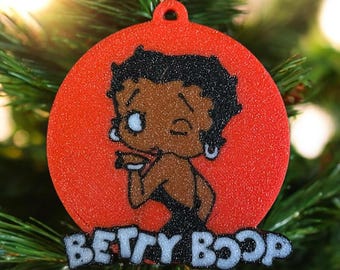 May include: Red glitter Christmas ornament featuring a cartoon image of Betty Boop with the text "BETTY BOOP" underneath.