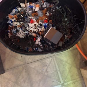 May include: A black plastic bin filled with a variety of colorful yarn scraps and a small brown box.