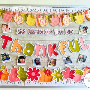 May include: A bulletin board decorated for Thanksgiving with the words "26 Reasons to be Thankful." The board features photos, colorful cutouts of pumpkins, leaves, and a turkey, and a banner of decorative shapes.