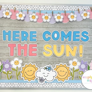 May include: A decorative bulletin board with the phrase "HERE COMES THE SUN!" in large, colorful letters. The board is adorned with flower and sun cutouts, and a banner of flowers. The background has a wood grain pattern.
