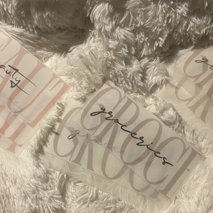 May include: Three white paper bags with the words "beauty" and "groceries" written on them in black cursive script.