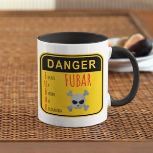 Puede incluir: Taza de café blanca con interior y asa negros. La taza presenta una señal de advertencia amarilla y negra con el texto "DANGER FUBAR" y el acrónimo escrito como "F*cked Up Beyond All Recognition". Un cráneo y huesos cruzados están en el centro del letrero.