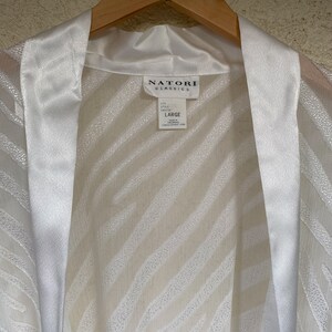May include: White satin robe with a zebra print pattern. The robe has a satin collar and a tie closure. The label reads "Natori Classics" and "Large".