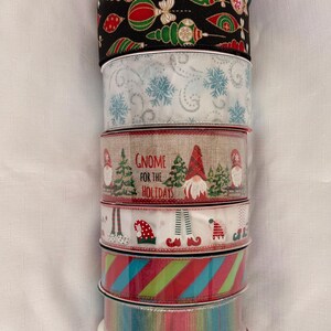May include: A stack of decorative Christmas ribbons in various designs. The ribbons feature patterns like snowflakes, ornaments, gnomes, and candy canes. Colors include red, green, white, and blue, perfect for holiday crafting and gift wrapping.