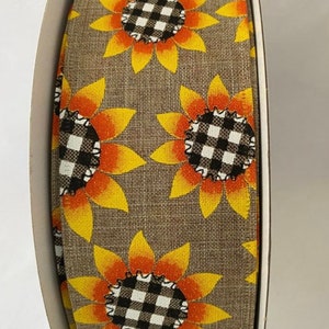 May include: A roll of brown burlap ribbon with a repeating pattern of yellow and orange sunflowers with black and white checkered centers.