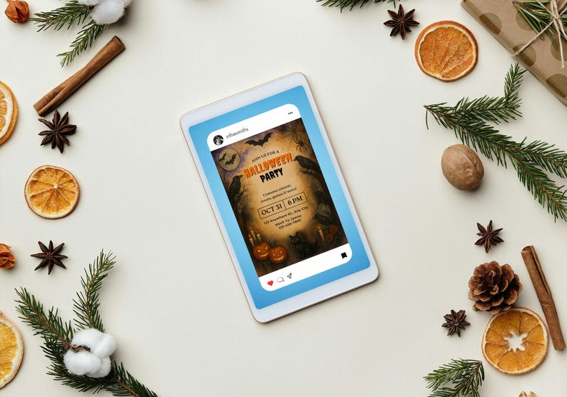 May include: A digital tablet displays a Halloween party invitation with bats, crows, and pumpkins. The invitation reads "Join us for a Halloween Party" with the date "Oct 31 6 PM". The tablet is surrounded by festive decorations including pine, cinnamon sticks, and dried orange slices.