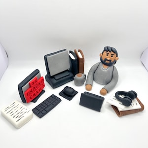 May include: A collection of miniature clay office items, including a computer, keyboard, and a figure of a person. The computer screen displays "36 UNREAD EMAILS". Other items include a coffee mug, books, and headphones.