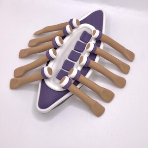 May include: A purple and white ceramic dish with eight brown ceramic sticks attached to the sides. The sticks have white and brown rings at the ends.