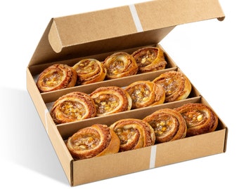 May include: A cardboard box with a lid, containing twelve baked pastries. The pastries are golden brown, swirled, and filled with a light-colored, sweet filling. The box is divided into three rows of four pastries each.