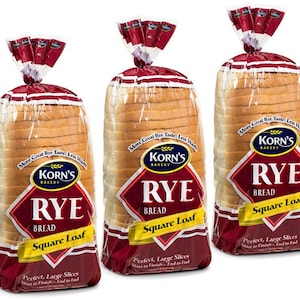 May include: Three loaves of Korn's Bakery Rye bread in clear plastic bags with red and white labels. The labels say "More Great Rye Taste, Less Waste" and "Korn's Bakery Rye Bread Square Loaf Perfect, Large Slices Start to Finish...End to End".
