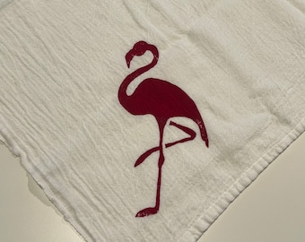 May include: A white kitchen towel with a red flamingo silhouette printed on it.