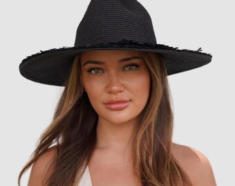 May include: A black wide-brimmed hat with a frayed edge. The hat is made of a woven material and has a slightly rounded crown.