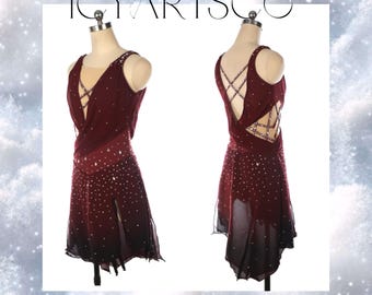 Puede incluir: Un vestido de patinaje artístico de color burdeos con un diseño de cruz en la espalda y una falda transparente con pedrería. El vestido tiene un escote en V y es sin mangas.