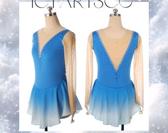 May include: Two ice skating dresses on mannequins. The dresses are blue with a gradient to white at the skirt hem. The bodice has a sheer nude mesh and is embellished with rhinestones. Long nude mesh sleeves complete the look. The text "ICY ARTSCO" is at the top.
