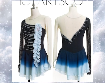 May include: Two ice skating dresses on mannequins. One dress features a black bodice with white and blue accents, a sheer sleeve, and a blue and white skirt. The other dress has a similar design. The text "ICY ARTSCO" is at the top.