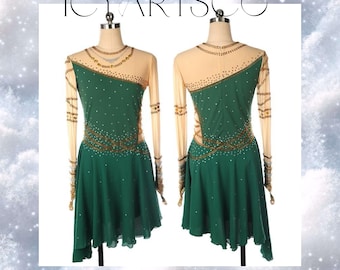 Puede incluir: Un vestido de patinaje artístico verde con mangas largas y una superposición transparente. El vestido tiene adornos dorados y plateados y un dobladillo asimétrico. El vestido está en un maniquí blanco.