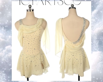 May include: A pale yellow figure skating dress with a draped chiffon overlay and a back that is open to the waist. The dress is embellished with rhinestones.