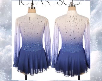 May include: A long-sleeved figure skating dress with a white to blue ombre design. The dress has a high neck and a fitted bodice with a flared skirt. The dress is decorated with small, sparkly rhinestones.