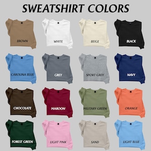 May include: A display of various sweatshirt colors, including brown, white, beige, and black. Other colors include Carolina blue, grey, sport grey, navy, chocolate, maroon, military green, orange, forest green, light pink, sand, and light blue. The text "SWEATSHIRT COLORS" is at the top.