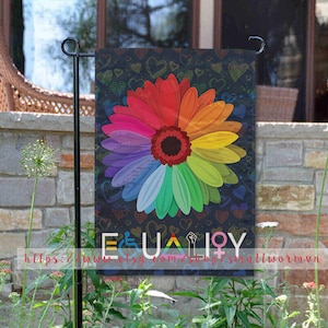 Puede incluir: Una bandera de jardín con un diseño de flor arcoíris y la palabra "IGUALDAD" escrita en letras negras. El fondo es negro con corazones blancos.