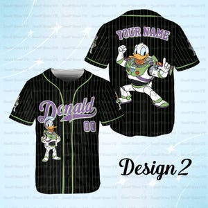 May include: Black baseball jersey with pinstripes, featuring the name "Donald" in purple script with the number "00". The jersey has a cartoon image of Donald Duck in a Buzz Lightyear costume. The back of the jersey has the text "YOUR NAME" and a Buzz Lightyear graphic.