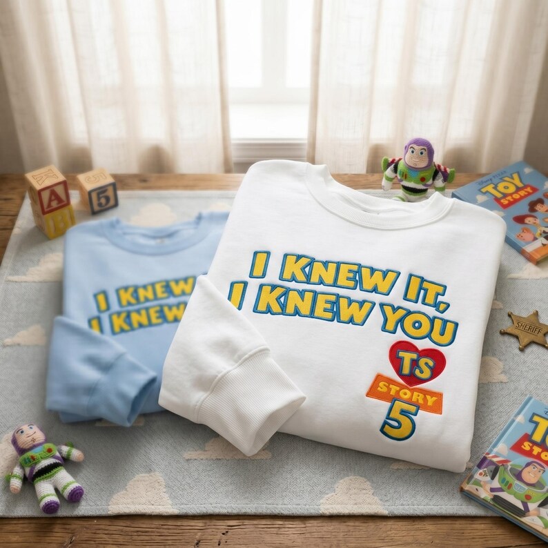 Puede incluir: Una sudadera blanca de cuello redondo con el texto I KNEW IT, I KNEW YOU, un coraz&oacute;n rojo con las letras TS y el texto STORY 5 en azul, amarillo y naranja. Una sudadera azul claro con el mismo texto se encuentra detr&aacute;s de la blanca.