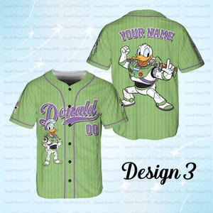May include: Green baseball jersey with vertical stripes, featuring "Donald" in purple script and the number "00". The front has a cartoon Donald Duck in a Buzz Lightyear-inspired outfit. The back displays "YOUR NAME" and a larger Donald Duck in the same outfit. "Design 3" is written below.