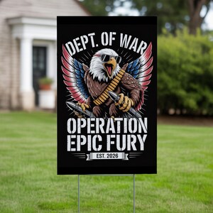 May include: A black yard sign with a graphic of an eagle wearing sunglasses and holding bullets. The sign reads "DEPT. OF WAR" above the eagle and "OPERATION EPIC FURY" below. The sign is on a metal stake in a grassy yard.