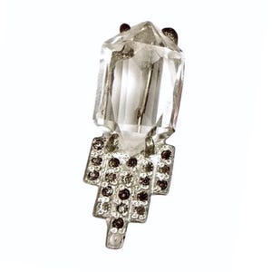 May include: A silver pendant featuring a clear crystal in the shape of a geometric prism. The crystal is set within a silver frame with a geometric design.