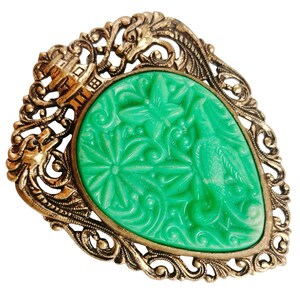 Könnte beinhalten: Vintage Brosche mit einem grünen, tropfenförmigen Mittelteil mit geschnitzten Blumen- und Vogelmotiven. Der Mittelteil ist von einem goldfarbenen, verzierten Filigranrand mit Drachen- und architektonischen Details umgeben. Ein einzigartiges, antikes Accessoire.