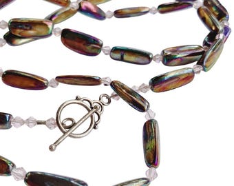 May include: An iridescent necklace with oblong beads in brown, green, and purple. Small, clear crystals are interspersed between the beads. The necklace is fastened with a silver toggle clasp.