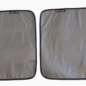 Puede incluir: Dos parasoles de malla gris para ventanas de coche con borde negro. Cada parasol tiene forma rectangular con esquinas redondeadas y costuras horizontales. Se ve un pequeño logotipo en la esquina superior derecha.