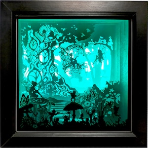 Puede incluir: Una obra de arte de papel recortado en 3D que representa una escena de hadas de fantasía. La escena presenta un gran árbol, hadas y hongos. La obra de arte está iluminada con una luz verde, creando una atmósfera mágica y encantadora.