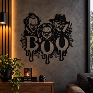 Op de afbeelding: Een zwart metalen wanddecoratie met de horrorfiguren Pennywise, Chucky en Freddy Krueger boven het woord BOO in een druipend lettertype, omringd door spinnenwebdetails voor een duistere en griezelige uitstraling.