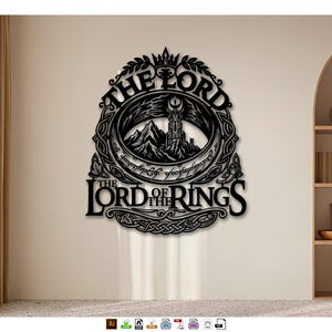 Könnte beinhalten: Ein schwarzes Wandkunstobjekt aus Metall mit dem Schriftzug THE LORD OF THE RINGS. Das Design zeigt einen Turm und Berge in der Mitte, umrahmt von einem Ring mit elbischer Schrift, gekrönt von einer Krone und kunstvollen Flechtmustern.