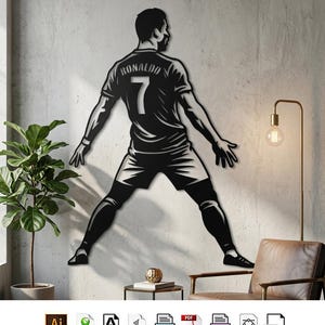 May include: A black metal wall art silhouette depicting a soccer player from behind, wearing a jersey with the name RONALDO and the number 7. The figure is shown in a wide stance with arms extended, rendered in a high-contrast graphic style.